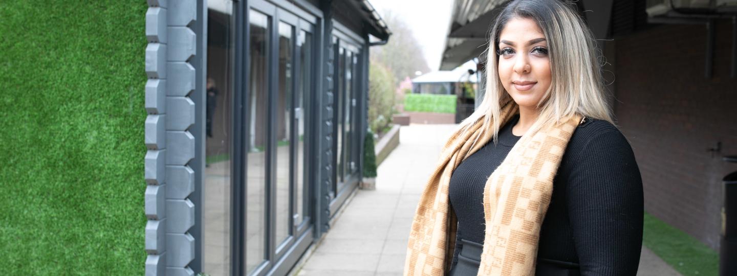 Woman stood outside in a courtyard wearing a bright scarf